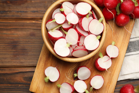 Fresh cut and whole radishes on wooden table, flat lay. Space for text