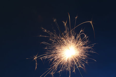 Bright burning sparkler on dark blue background, closeupの写真素材