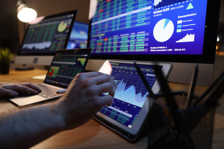 Financial trading specialist working on tablet in office at night, closeup