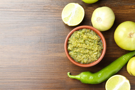 Delicious salsa sauce in bowl and products on wooden table, flat lay. Space for textの写真素材