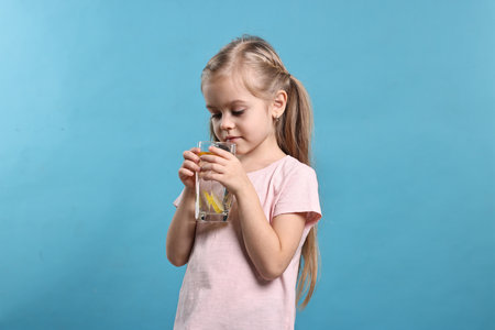 Girl with glass of lemonade on light blue background. Refreshing drinkの写真素材