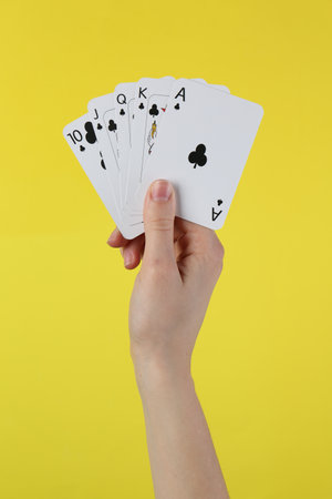 Woman with playing cards against yellow background, closeupの写真素材