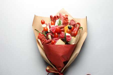 Beautiful edible bouquet with meat, cheese and tomatoes on white background, top viewの写真素材