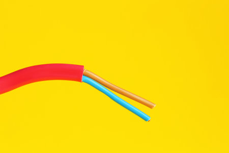 Red stripped electrical wire on yellow background, closeupの写真素材