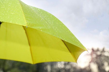 Open yellow umbrella under pouring rain outdoors, closeup. Space for textの写真素材
