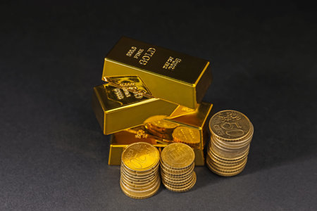 Gold bars and coins on black table, closeup