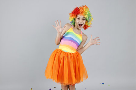 Happy girl dressed like clown on grey background. Surprise partyの写真素材