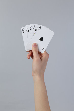 Woman with playing cards against grey background, closeupの写真素材