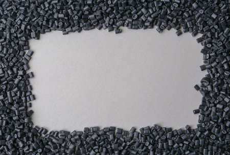 Frame of black plastic granules on gray background, top view. Space for textの写真素材