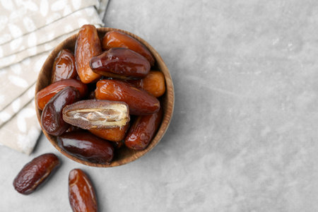 Tasty dried dates in bowl on light gray table, top view. Space for textの写真素材