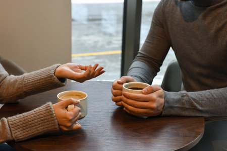 Colleagues talking during coffee break at wooden table in cafe, closeup