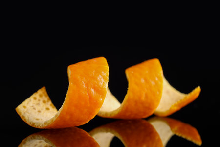 One curly orange peel on black mirror surface, closeupの写真素材