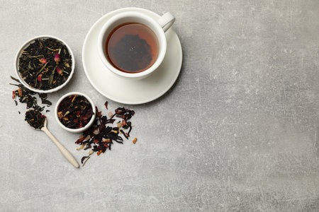 Aromatic tea and dried leaves on grey table, flat lay. Space for textの写真素材