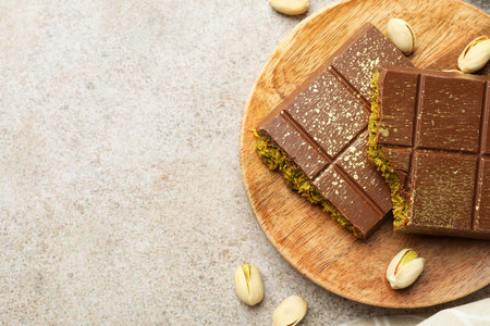 Pieces of chocolate bar with pistachios and knafeh on grey table, top view. Space for textの写真素材