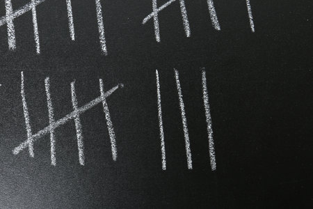 Counting days by drawing sticks with chalk on blackboard, closeupの写真素材