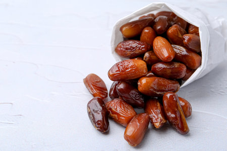 Tasty sweet dried dates in paper bag on white table, closeup. Space for textの写真素材