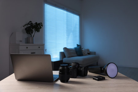 Professional photo camera, lens, flash and laptop on wooden desk indoors. Space for textの写真素材