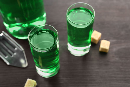 Absinthe in shot glasses, brown sugar and slotted spoon on wooden table, closeupの写真素材