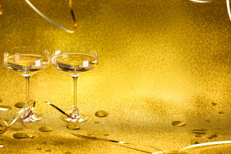 Champagne in glasses, confetti and streamers on golden background. Space for textの写真素材