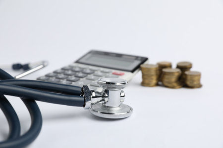 Stethoscope, calculator and coins on light background, closeupの写真素材