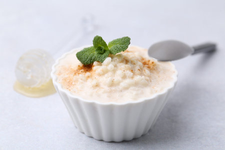 Tasty rice pudding with cinnamon and mint on light gray table, closeupの写真素材
