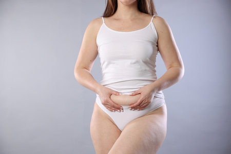 Woman in underwear on light grey background, closeup. Cellulite problemの写真素材