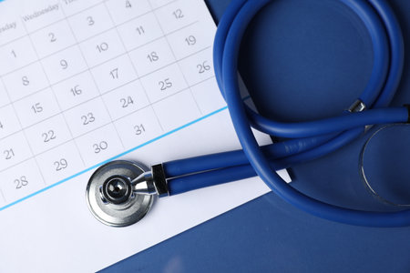 Stethoscope and calendar on blue background, top viewの写真素材