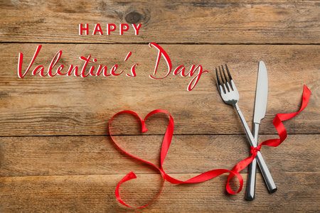Happy Valentine's day card. Red heart made of ribbon and cutlery on wooden table, top viewの写真素材