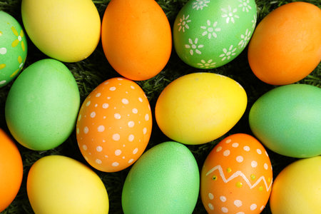 Beautiful decorated Easter eggs on green grass, flat layの写真素材