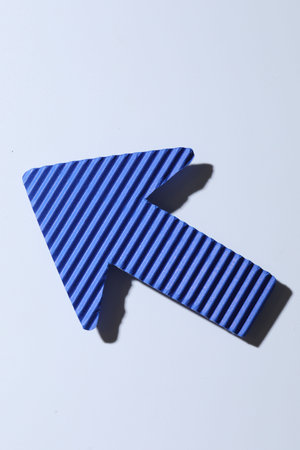 One blue paper arrow on white background, top view