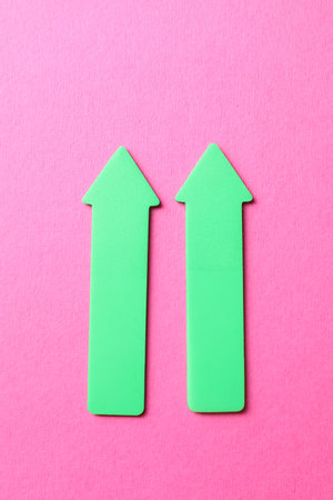 Green arrows on pink background, top viewの写真素材