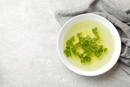 Chicken bouillon with parsley in bowl on grey table, top view. Space for textの写真素材