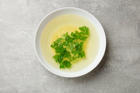 Tasty chicken bouillon with parsley in bowl on grey table, top viewの写真素材