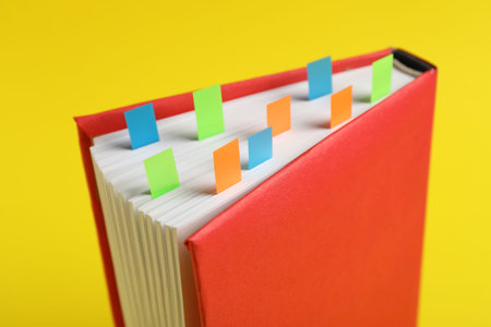 Book with colorful tabs on yellow background, closeupの写真素材