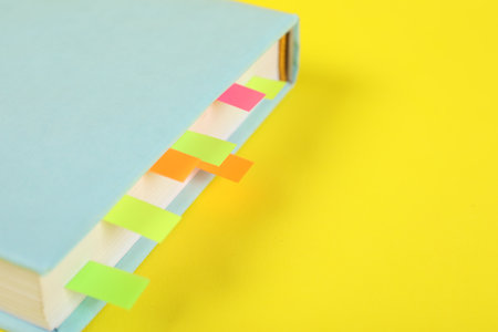 Book with colorful tabs on yellow background, closeup. Space for textの写真素材