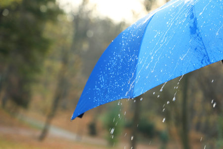 Open blue umbrella under pouring rain outdoors, closeup. Space for textの写真素材