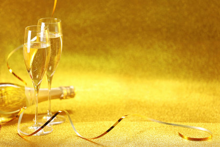 Champagne in glasses and bottle on golden background. Space for textの写真素材