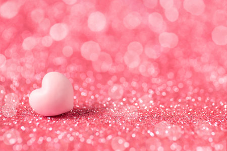 Valentine's day greeting card. Small heart on shiny pink glitter and bokeh lights. Space for textの写真素材