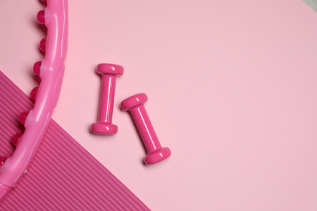 Dumbbells, hula hoop and fitness mat on pink background, flat lay. Space for textの写真素材
