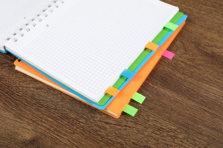 Notebooks with colorful tabs on wooden table, closeup