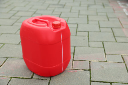 One red plastic canister on pavement outdoors, space for textの写真素材