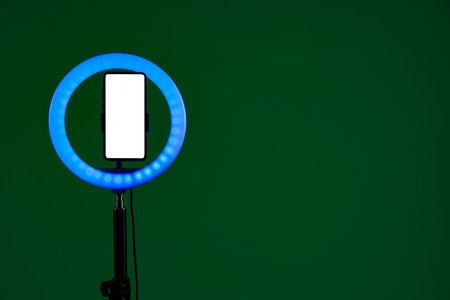Ring lamp with smartphone on green background, space for textの写真素材