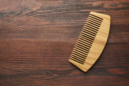 One hair comb on wooden background, top view. Space for text
