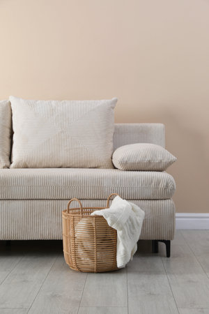 Comfortable sofa with pillows and basket near beige wallの写真素材
