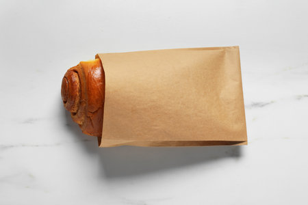 Paper bag with bun on white marble table, top viewの写真素材