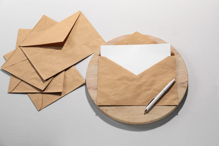 Kraft paper envelopes with letter and pen on gray background, flat lay. Mockup for design
