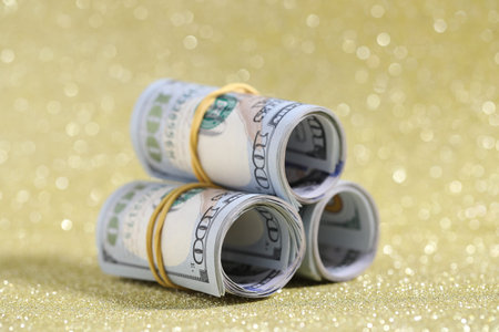 Many dollar banknotes on golden glitter background, closeup