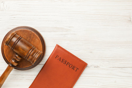 Passport in brown cover and judge's gavel on light wooden table, top view. Space for textの写真素材