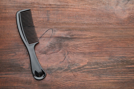 One black plastic comb on wooden background, top view. Space for textの写真素材