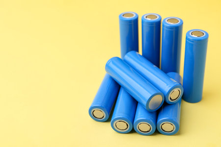 Many AA cell batteries on yellow background, closeup.の写真素材